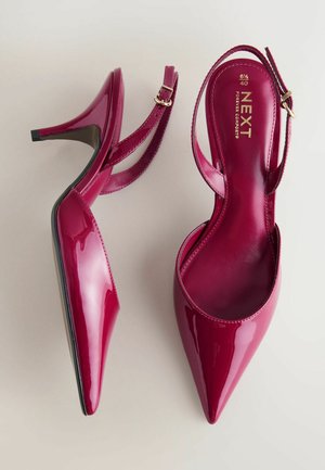 Scarpe con tacco alto lucide fucsia con punta appuntita, cinturino alla caviglia e suola nera. Logo dorato sulla soletta interna.