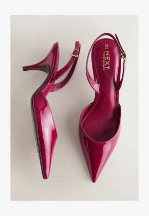 Błyszczące fuksjowe szpilki z zakrzywionym noskiem, paskiem na kostkę i czarną podeszwą. Złote logo na wewnętrznej wkładce.