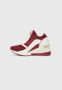 Scarpa sportiva rossa e bianca con design alto, tessuto in rete, dettaglio della zip dorata e una suola a forma di cuneo elegante.