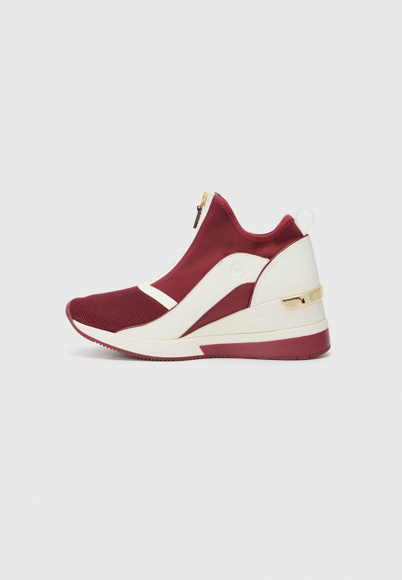 Scarpa sportiva rossa e bianca con design alto, tessuto in rete, dettaglio della zip dorata e una suola a forma di cuneo elegante.