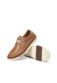 Zapatos de cuero marrón con puntera redondeada, detalles de costura, acentos de hardware plateado y una suela beige moteada. Adecuados para uso casual.