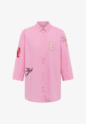 Chemise rose à manches longues avec boutons, brodée d'une lettre C, d'un homard rouge sur la manche gauche, d'un oiseau noir sur le devant et d'étoiles jaunes sur la manche droite.