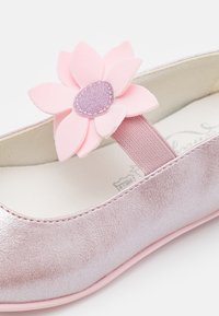 Ballerine métallique rose avec un ornement floral en tissu, présentant un dessus texturé, un bout arrondi et une sangle élastique.