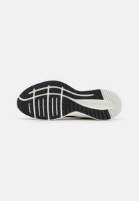 Suela de zapato con un patrón de agarre de goma negra, entresuela blanca y detalles texturizados para proporcionar tracción y estabilidad.