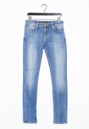 Jasnoniebieskie dżinsy z denimu z wyblaknięciami na udach i kolanach, w stylu z pięcioma kieszeniami, wiszące na czarnym wieszaku na białym tle.