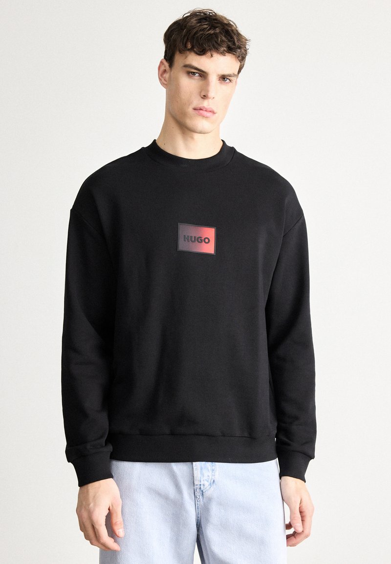 Μαύρο φούτερ με λαιμόκοψη crew, που φέρει ένα ορθογώνιο λογότυπο σε κόκκινο και μαύρο. Κομμένο σε άνετη γραμμή με ριμπ μανσέτες και τελείωμα.