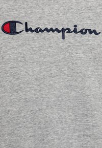 Sudadera gris de algodón con el logo bordado "Champion" en cursiva azul oscuro, con un detalle rojo dentro del diseño del logo.