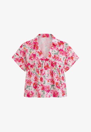 Rövid ujjú, V-nyakú blúz rózsaszín, piros és narancssárga virágmintával fehér alapon.