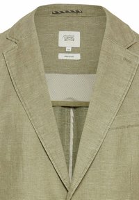 Beige linnenblazer in een gemengde stof met een gestructureerde weving, notch revers en een enkele borstzak. Het label aan de binnenkant geeft maat 50 en het type stof aan.