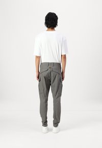 Γκρίζα Cargo παντελόνια με πλαϊνές τσέπες, κομμένο σε στενή γραμμή και ζώνη με ετικέτα. Συνδυασμένα με μια απλή λευκή μπλούζα και λευκά αθλητικά παπούτσια.