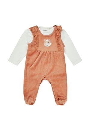 Oranges Velours-Overall mit Rüschenträgern und einem Affengesicht-Applikation, kombiniert mit einem weißen Langarmhemd darunter. Weicher Stoff.