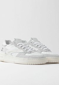 Sneakers bianchi con una combinazione di texture liscia e scamosciata, caratterizzati da una suola spessa, perforazioni circolari e sottili accenti grigi.