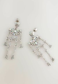 Pendientes en forma de esqueleto en tono plateado con rhinestones iridiscentes y cierre de presión sobre fondo claro.