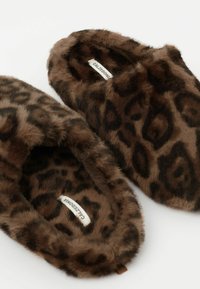 Faux fur slippers med et brunt leopardprint-design, der har en blød, luksuriøs tekstur og en lukket tå. Brandmærke synligt indeni.