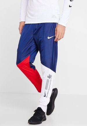 Spodnie dresowe Nike z kolorowym blokowym wzorem w granatowym, czerwonym i białym kolorze, z detalami logo, gładką fakturą i zwężanym krojem.