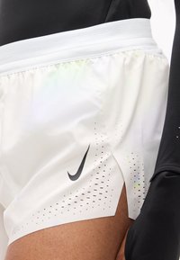 Λευκά αθλητικά σορτς με μαύρο λογότυπο Nike, που διαθέτουν διάτρητα σημεία κατά μήκος του τελείου και υφή στη μέση για καλύτερη εφαρμογή και άνεση.
