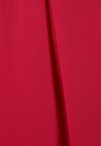 Punane kangas, millel on sile tekstuur ja vertikaalne volt detaili lisamiseks. Üldmulje on julge ja erksavärviline.