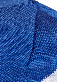 Tessuto a maglia blu con un motivo a righe diagonali, texture liscia e un accento bianco a contrasto, con cuciture dettagliate visibili.