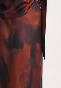 Long-sleeve dress featuring a multicolored abstract pattern in shades of red, black, and dark purple. Smooth texture with flowing fabric.