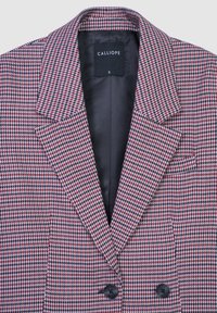 Blazer in misto lana con motivo a scacchi rosso e nero, presenta revers a punta e due bottoni neri. All'interno ha una fodera nera liscia.