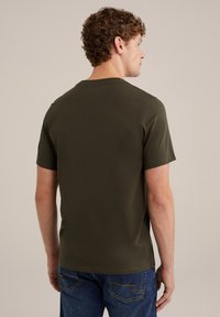 Tricou scurt de culoare verde măslin, cu decolteu rotund clasic, realizat dintr-un material moale. Purtați-l cu blugi albaștri, având un design simplu și curat.