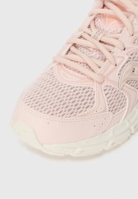 Rosa Mesh-Laufschuh mit einem atmungsaktiven Obermaterial, strukturierten Overlays und leichter Dämpfung. Verfügt über passende Schnürsenkel und eine weiße Sohle.