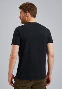 Zwart katoenen T-shirt met ronde hals en korte mouwen, met een eenvoudige achterkant en een ontspannen pasvorm. In combinatie met shorts is zichtbaar.