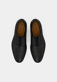 Chaussures noires en cuir lisse avec un bout arrondi, comprenant six œillets, des coutures discrètes et un panneau avant texturé.