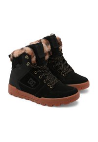 Botas de tobillo negras hechas de ante y material sintético. Con forro de pelaje sintético, ojales dorados y suela de goma marrón.