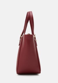 Rote, dreieckige Handtasche aus strukturiertem Leder mit einem oberen Griff. Goldfarbene Hardware-Details an der Basis des Griffs zur Befestigung.