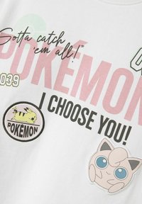 Vit bomull t-shirt med stor rosa text "POKEMON JAG VÄLJER DIG!" och broderade lappar av Pikachu och Jigglypuff.