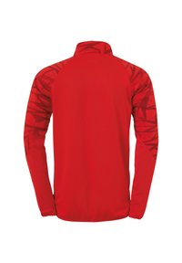 Giacca sportiva rossa a maniche lunghe con colletto alto e astratti motivi geometrici rosso scuro sulle maniche e sulle spalle.