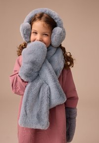 Lichtblauwe nepbont oorwarmers, sjaal en wanten. Zachte textuur met afgeronde vormen. Gecombineerd met een roze longsleeve met textuur.