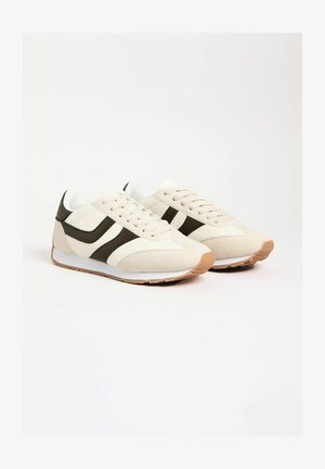 Skrienēšana ar bēšu zamšādas un sieta augšdaļu, tumši zaļām akcentu svītrām, baltām vidējām zolēm un brūnu gumijas ārējo zoli.