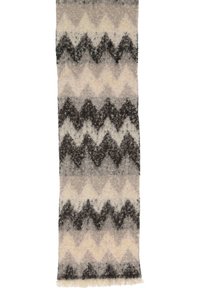Tapis rectangulaire présentant un motif en zigzag dans des nuances de gris, de crème et de noir, avec une texture douce et des bords à franges pour le détail.