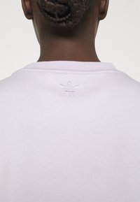 Vit bomullen T-shirt med rund halsringning och subtilt broderad Adidas-logotyp på baksidan. Mjuk, slät textur med en avslappnad passform.