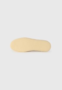 Podešev boty, béžový gumový materiál, hladký povrch, zaoblený tvar, žádné viditelné vzory nebo kování. Minimalistický design, neutrální barva.