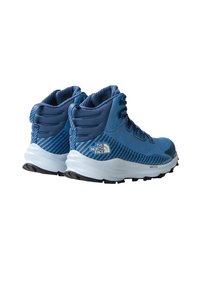 Bottes de randonnée bleues avec une tige en mesh texturé, un col rembourré et un logo blanc. La semelle est blanche avec des motifs de traction noirs.