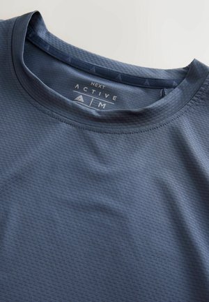 Temno modra teksturirana športna majica z okroglim izrezom, velikost srednja, z vidno etiketo blagovne znamke "NEXT ACTIVE" znotraj ovratnika.