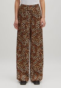 Leopardprint wijdere broeken gemaakt van zachte stof, met een elastische tailleband en levendige oranje, zwarte en tan kleuren.