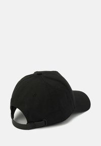 Gorra de béisbol negra hecha de algodón. Presenta un visera curva, correa ajustable y una superficie texturizada con detalles de costura en la corona.