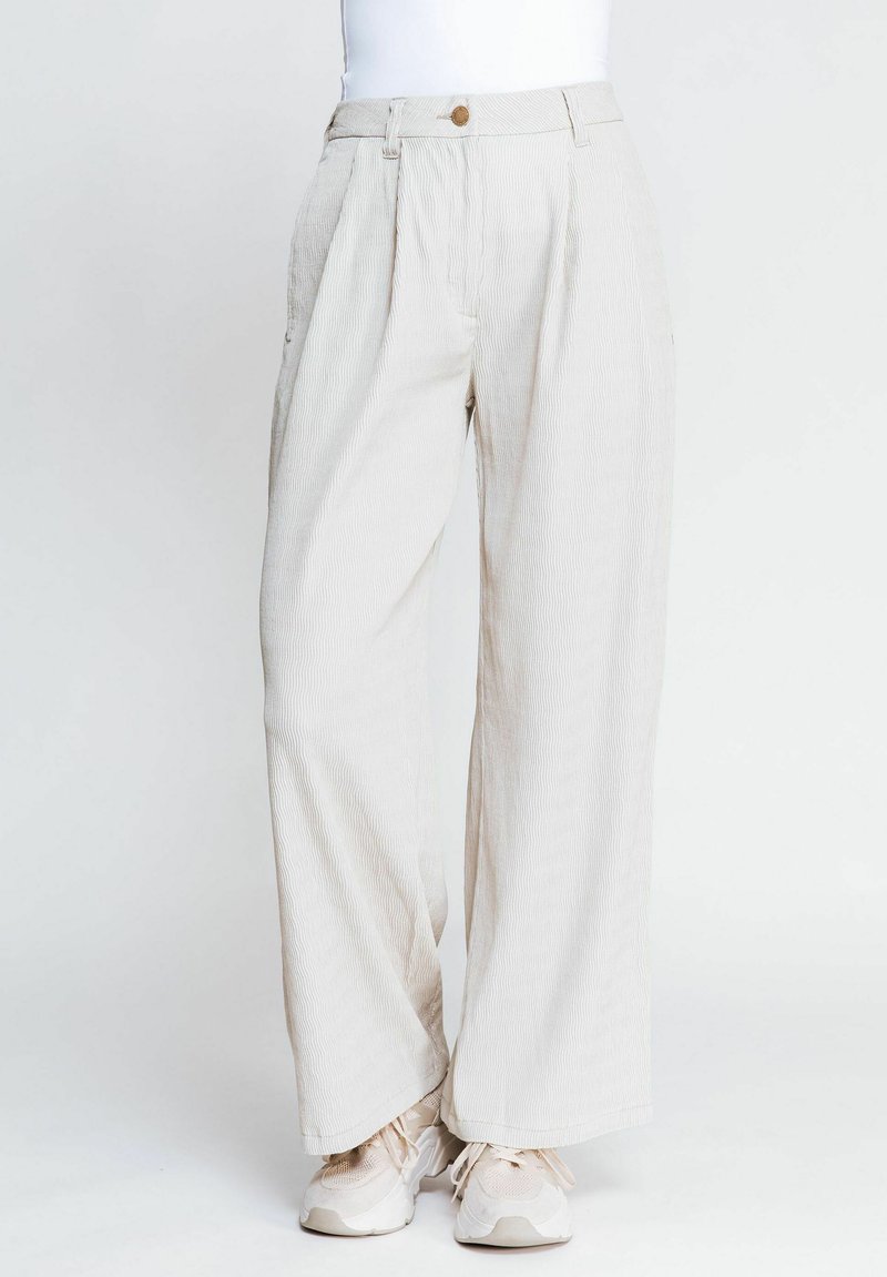 Helle beigefarbene weit geschnittene Hose mit vertikaler Rippstruktur, ausgestattet mit einem vorderen Fall, einem Knopf an der Taille und seitlichen Taschen.