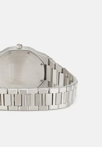 Silver stainless steel watch with an octagonal face and a rectangular link bracelet. Features a polished finish and engraved brand name on the band.
