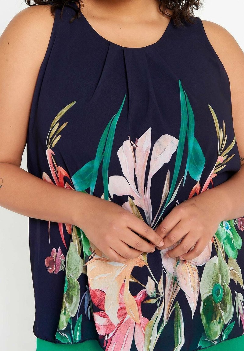 Marinblus utan ärmar med veckad halsringning, med ett livfullt blommönster i rosa, grön och gul. Lättviktsmaterial, lös passform.