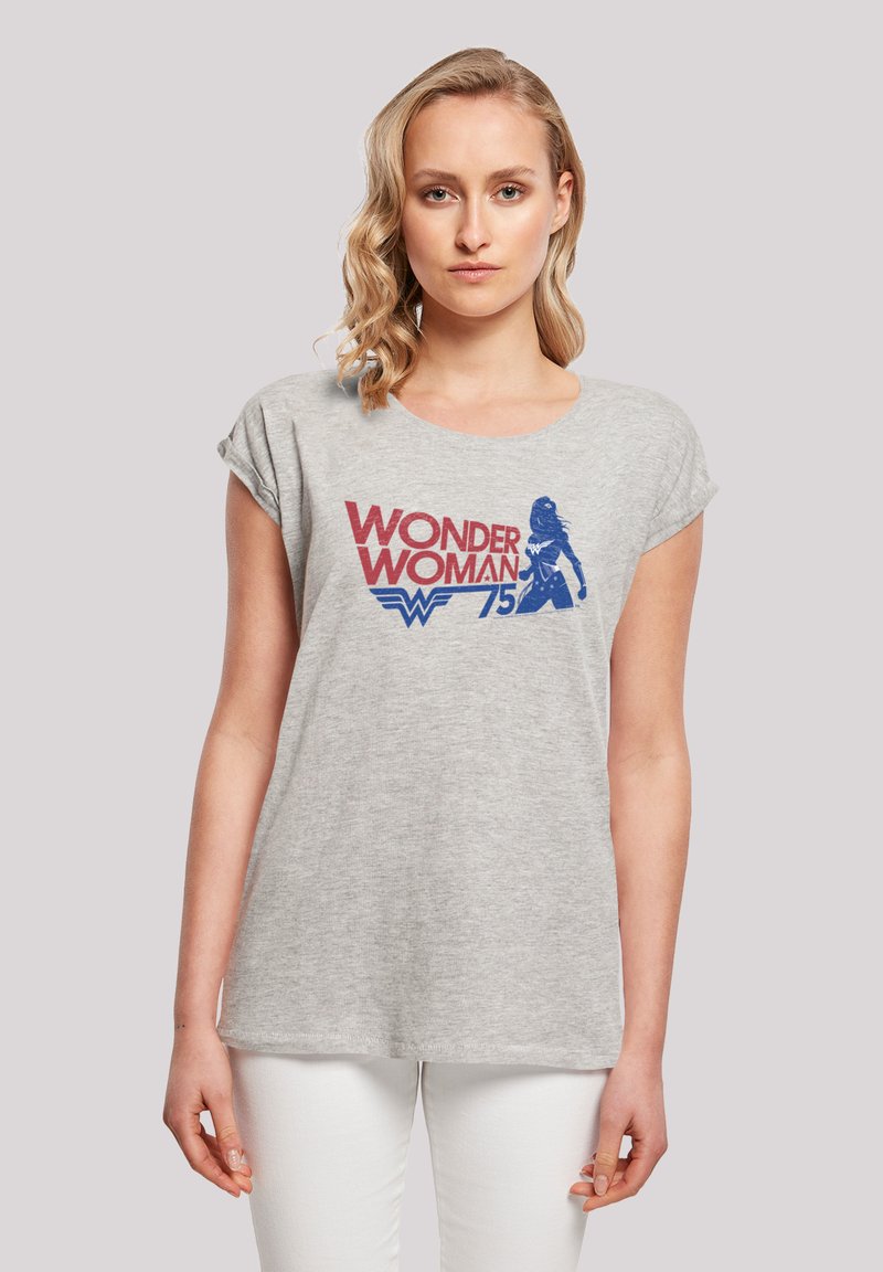 Grå t-skjorte med rullede ermer som har et rødt og blått grafisk design av "Wonder Woman" og tallet "75" trykt på forsiden.