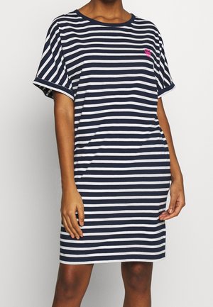 Kvinde iført en kortærmet, knælængde kjole med navy og hvide vandrette striber og et lille pink logo på den øverste brystdel.