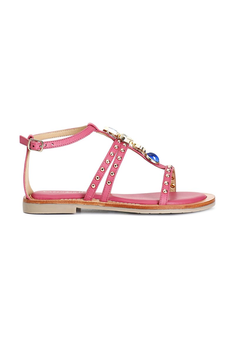 Sandaletta piatta rosa in materiale sintetico, con molteplici cinturini decorati con borchie dorate e pietre decorative, e una soletta imbottita.