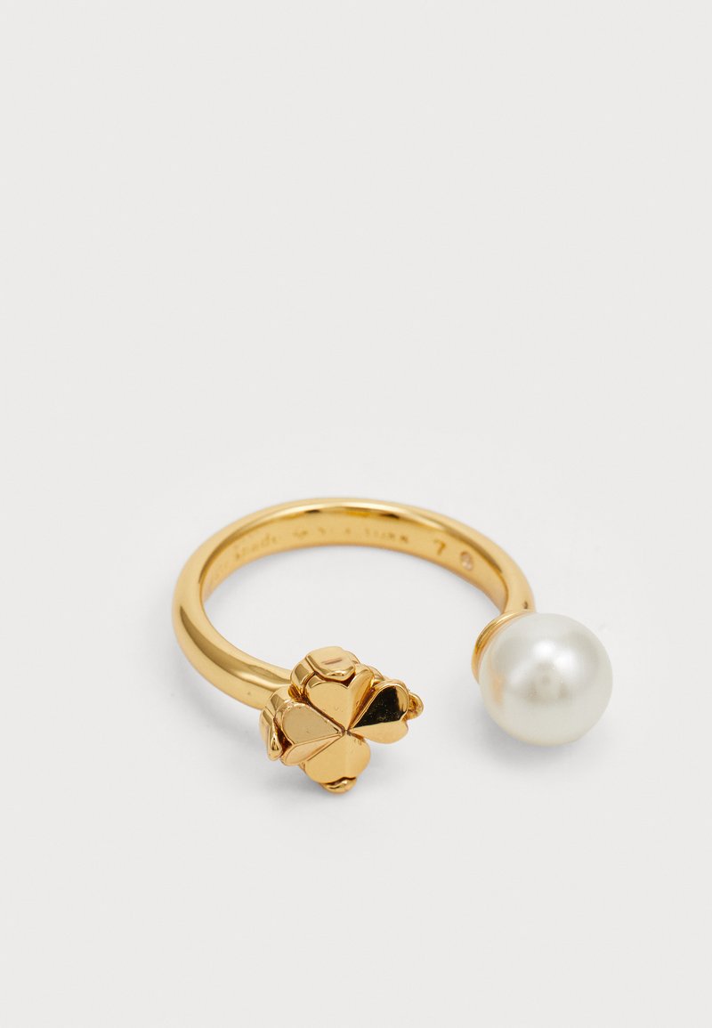 Zlato tonirana prstna obroček z cvetličnim vzorcem na eni strani in velikim belim biserom na drugi. Gladka površina, velikost 7.