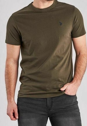 Olivengrøn kortærmet t-shirt lavet af blødt stof, med et lille sort logo på brystet, kombineret med mørke jeans.