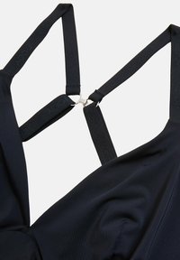 Zwart stoffen mondkapje met verstelbare elastische bandjes die verbonden zijn door een centrale zilveren metalen klem.